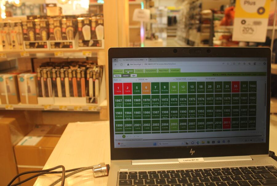 Voorraadcontrole op een laptopscherm met winkelschappen op de achtergrond